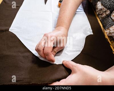 femme fixe la disposition en papier de la robe à un tissu brun par code pin à la maison Banque D'Images