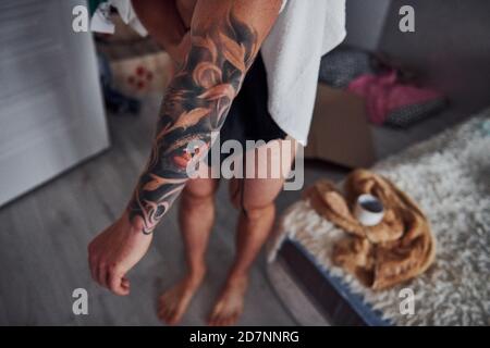 Guy montre son tatouage sur le bras à l'intérieur à la maison après la douche Banque D'Images