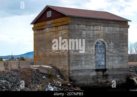 Une ancienne centrale hydro-électrique. La mousse pousse sur les côtés en béton décoloré. Fenêtre voûtée face à l'eau. Ciel couvert. La station n'est plus en nous Banque D'Images