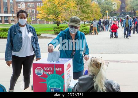 Brooklyn, NY, États-Unis. 24 octobre 2020. Une ligne de personnes désireuses de voter s'est étirée sur 1 km (0.6 mi) une demi-heure après l'ouverture des sondages le premier jour de vote par anticipation à New York. Les portes du bureau de vote de l'université de Brooklyn, dans le quartier de Midwood, ont ouvert aux électeurs à 10 h 00, et un employé du bureau de scrutin a signalé que la première personne à arriver aux portes à 4 h 30 ce matin. Une femme évite la ligne en amenant son bulletin de vote absent et en le déposant. Credit: Ed Lefkowicz/Alay Live News Banque D'Images