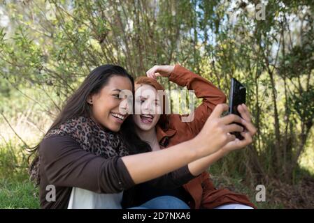 deux femmes multiraciales qui font un selfie dans le parc Banque D'Images