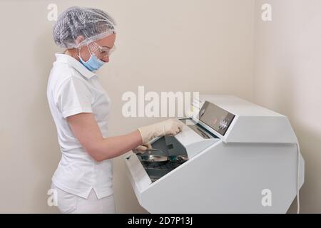 Infirmière féminine stérilisant des instruments médicaux dentaires en autoclave Banque D'Images