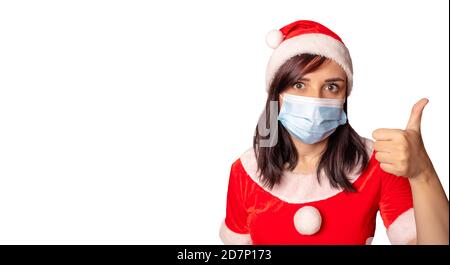 La jeune femme en costume du Père Noël montre les pouces sur fond blanc. Gros plan d'une femme dans un chapeau de Noël montrant un geste d'approbation. Concept de Banque D'Images