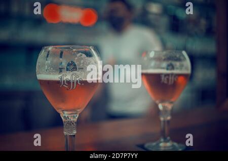 Accent sélectif sur un verre de bière. Arrière-plan flou d'un serveur portant un masque facial. Banque D'Images