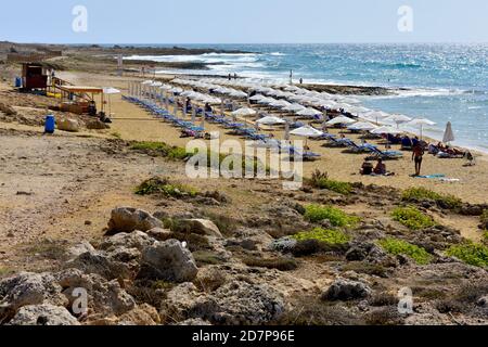 Plage de Chrysi Ammos avec station de garde, chaises longues, parasols sur le sable avec mer bleue, Paphos, Chypre Banque D'Images