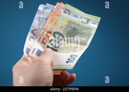 Main tenant l'argent sur un fond bleu Banque D'Images