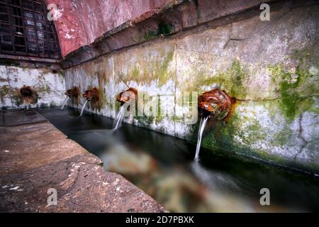 Bouches en fonte à Lavatoio Medievale, lavoir médiévale. Cefalù, Sicile, Italie. Banque D'Images