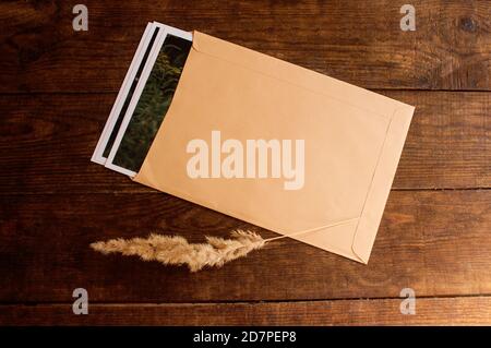 les photos sont jointes dans une enveloppe beige, située sur une table en bois marron Banque D'Images