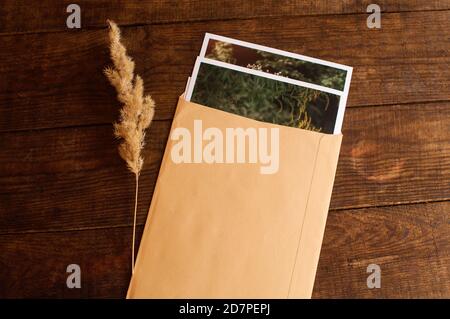 les photos sont jointes dans une enveloppe beige, située sur une table en bois marron Banque D'Images