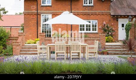 Grande maison de campagne britannique avec meubles de jardin sur un patio dans un jardin à l'arrière Banque D'Images