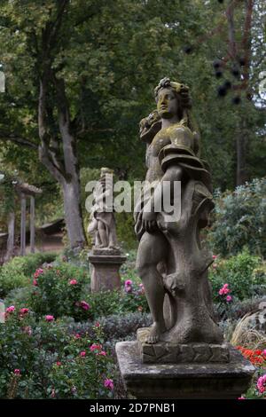 Une ancienne statue d'une déesse se trouve dans un jardin botanique de Rothenburg ob der Tauber, recouvert de mousse verte, parmi les fleurs. Banque D'Images