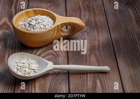 Tasse en bois et cuillère avec flocons d'avoine. Santé alimentaire. Texture du bois Banque D'Images