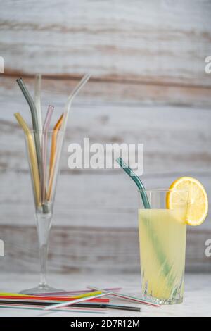 Limonade à la paille de verre. Pailles en verre remplaçant les pailles en plastique dans le verre avec fond en bois. Banque D'Images