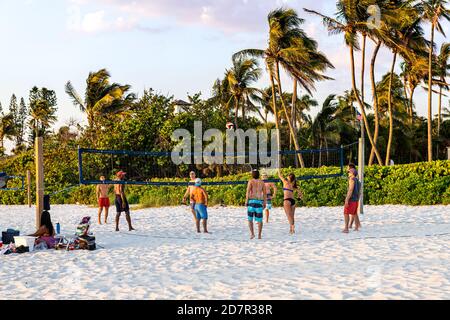 Naples, États-Unis - 29 avril 2018 : coucher de soleil en Floride sur la côte du golfe du Mexique avec des personnes jouant au volley-ball sportif sur le sable avec des palmiers Banque D'Images