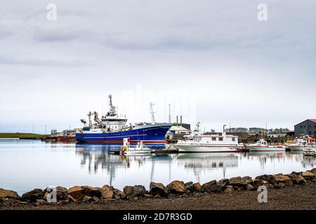 Hofn, Islande - 15 juin 2018 : petit village de pêcheurs port de la ville marina avec bateaux bleus les navires reflètent dans l'eau Banque D'Images