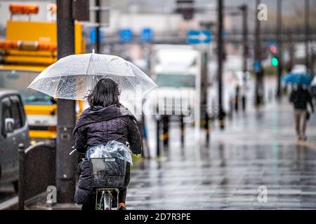 Kyoto, Japon - 10 avril 2019 : rue GOJO-dori pendant les jours de pluie et personnes femme vélo tenant un parapluie sur le trottoir Banque D'Images