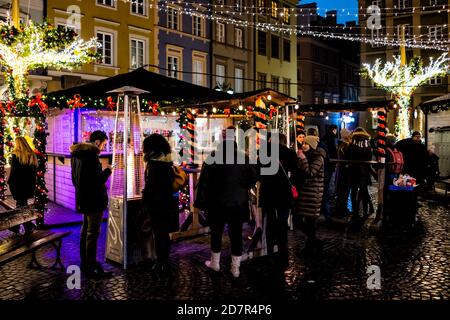 Varsovie, Pologne - 19 décembre 2019 : place du marché de la vieille ville de Varsovie la nuit avec décoration illuminée de Noël, personnes buvant du chocolat chaud, mu Banque D'Images