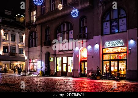 Lviv, Ukraine - 27 décembre 2019 : place du marché de la vieille ville avec des gens la nuit en café, magasins et magasins d'Yves Rocher France et restaurant Varenik Banque D'Images