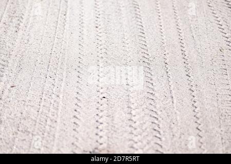 Plusieurs modèles de pneus de véhicule dans du sable blanc mou. Les roues ont créé un motif triangulaire et plusieurs lignes en zigzag. Banque D'Images