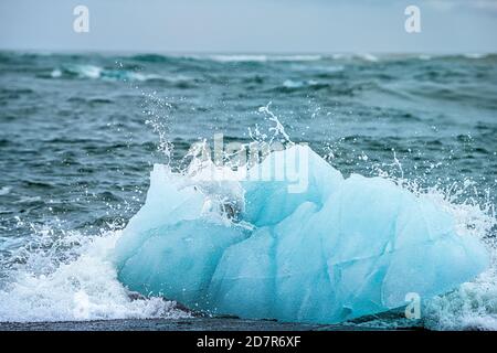 Vagues se brisant sur la plage glaciaire de Jokulsarlon Diamond Ice en Islande Face à l'iceberg du glacier avec des éclaboussures d'eau sur l'océan Atlantique Banque D'Images