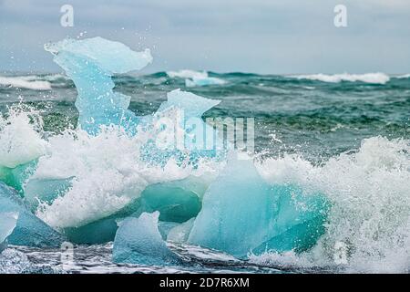 Les vagues se brisent sur la plage glaciaire de Jokulsarlon Diamond Ice L'Islande contre l'iceberg du glacier avec des éclaboussures d'eau sur l'océan Atlantique Banque D'Images