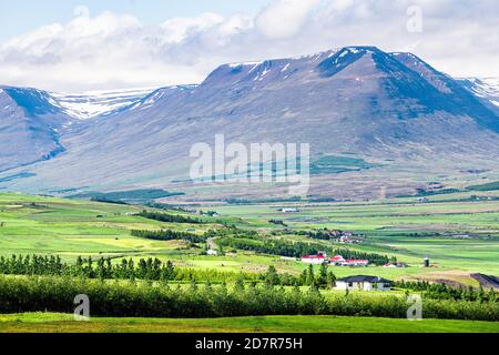 Vue sur les montagnes Sulur près d'Akureyri avec des nuages bleus et le paysage pastoral de ferme de pâturage avec de l'herbe verte pendant l'été jour Banque D'Images