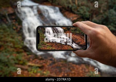 Personne tenant un téléphone portable prenant une photo de Merry Falls - DuPont State Recreational Forest - Cedar Mountain, près de Brevard, Caroline du Nord, Etats-Unis [Co Banque D'Images