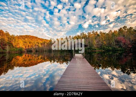 Jetée en bois sur le lac dense en automne avec des reflets de nuages - DuPont State Recreational Forest - près de Cedar Mountain, Caroline du Nord, États-Unis Banque D'Images