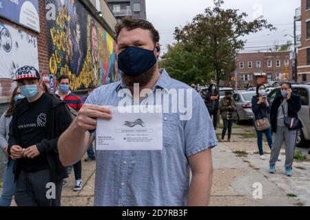 New York, États-Unis. 24 octobre 2020. Un homme tient un bulletin de vote absent alors qu'il le livre en personne à un bureau de vote du Lincoln Center lors du vote par anticipation pour l'élection présidentielle américaine.en raison du coronavirus et des préoccupations sociales de distanciation l'État de New York permet le vote par anticipation pour la première fois. Crédit : SOPA Images Limited/Alamy Live News Banque D'Images