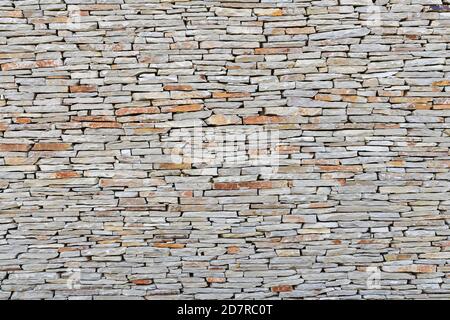 Gros plan d'un mur en pierre fait de petites pierres plates. Concept abstrait et géométrie. Banque D'Images
