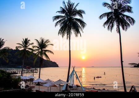 Coucher de soleil se reflétant sur la surface de l'eau au premier plan avec la zone des cococotiers ao bang Bao à l'île de Koh kood est un district de la province de Tran. Thaïlande. Banque D'Images