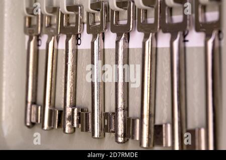 Rangée de vieilles clés métalliques en argent squelette accrochées dans le rack avec les numéros de la pièce. Clés anciennes millésimes Banque D'Images