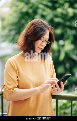 Femme mature vérifiant le téléphone Banque D'Images