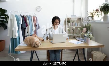 Une femme de créateur se réjouit de jouer avec un lapin sur un ordinateur portable Banque D'Images