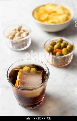 Apéritif composé de vermouth rouge, d'olives, de pistaches et de chips. Table en marbre Banque D'Images