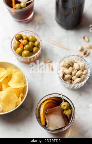 Apéritif composé de vermouth rouge, d'olives, de pistaches et de chips. Table en marbre Banque D'Images