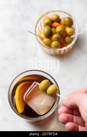 La main de l'homme cueillant des olives de vermouth rouge. Vue de dessus Banque D'Images