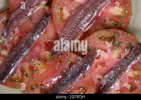 Gros plan des tranches de tomate rouge avec des anchois sur un plaque jaune Banque D'Images