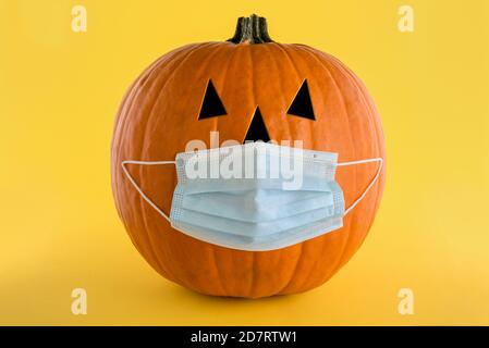 Citrouille d'Halloween avec un masque médical pour la protection du coronavirus (covid-19) Sur fond jaune.concept de protection Banque D'Images