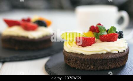 Petits gâteaux au chocolat avec fromage à la crème, fruits et baies. Mini-gâteau comme dessert de café sain. Gros plan, mise au point sélective Banque D'Images