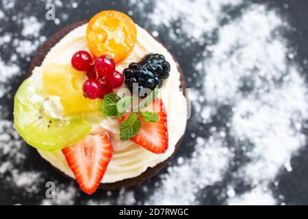 Mini-gâteau au chocolat avec fromage à la crème, fruits et baies. Vue de dessus, espace de copie. Gros plan, faible profondeur de champ Banque D'Images