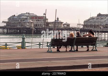 Les gens sur la promenade près de Brighton et de son dangereux West Pier. Il a été conçu par Eugenius Birch et a ouvert ses portes en 1866. Il a été le premier quai à être classé Grade I en Grande-Bretagne, mais est devenu de plus en plus délabrée depuis sa fermeture au public en 1975. 20 juillet 1995. Photo: Neil Turner Banque D'Images