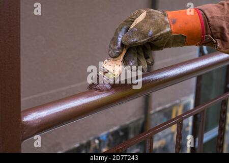 Main de l'entrepreneur avec une brosse qui peint la construction de la main courante en métal. Banque D'Images