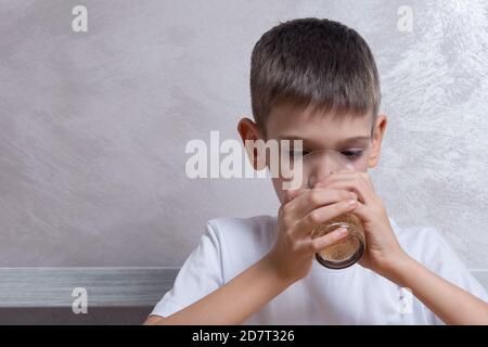 Un beau garçon boit de l'eau pétillante provenant d'un verre, gros plan, espace de copie. Concept alimentaire malsain, nourriture préférée des enfants Banque D'Images