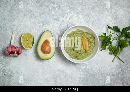 guacomole dans un bol blanc, avocat frais sur fond de béton gris. vue de dessus. Banque D'Images