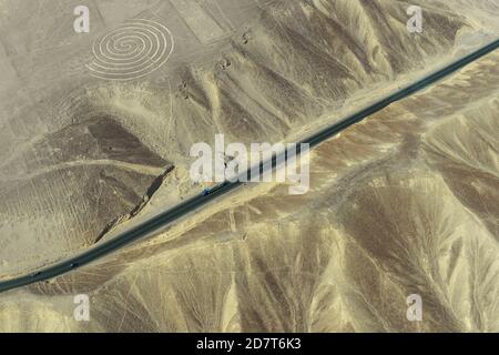 Vue aérienne du géoglyphe en spirale dessinant dans le désert péruvien connu sous le nom de lignes mystérieuses de Nazca avec l'autoroute panaméricaine près de la ville de Nazca, Pérou. Banque D'Images