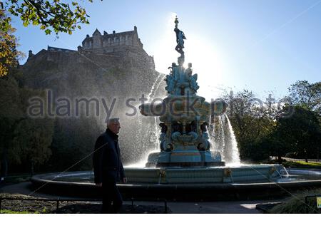 Édimbourg, Écosse, Royaume-Uni. 25 octobre 2020. Vents violents créant beaucoup de jets sur la fontaine Ross, normalement tranquille, des jardins de West Princes Street, les piétons prenant soin de ne pas se mouiller. Le soleil rétro-éclairé et filtrant à travers le spray, avec une vue sur le château d'Édimbourg. Crédit : Craig Brown/Alay Live News Banque D'Images