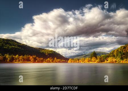 Couleurs d'automne sur le lac Ghirla à Valganna avec des nuages déplacés par le vent, exposition longue durée Banque D'Images