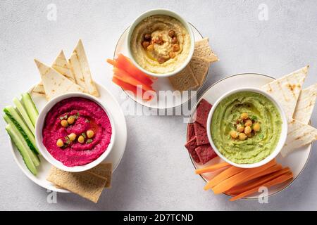 houmous colorés dans des bols, servis avec des bâtonnets de légumes et des craquelins. Banque D'Images