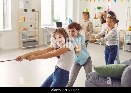 Des enfants heureux jouant du remorqueur de guerre à la fête à la maison ou au club de loisirs pour les enfants Banque D'Images